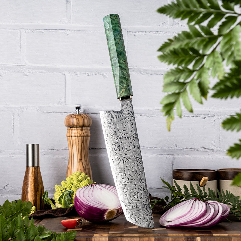 Decorative nakiri knife with green handle on a wooden cutting board with vegetables and kitchen items.