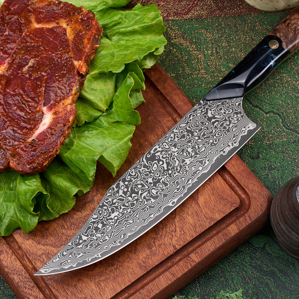 A large Damascus steel carving knife with a patterned steel blade and a black handle, resting on a wooden cutting board next to raw beef and green lettuce.