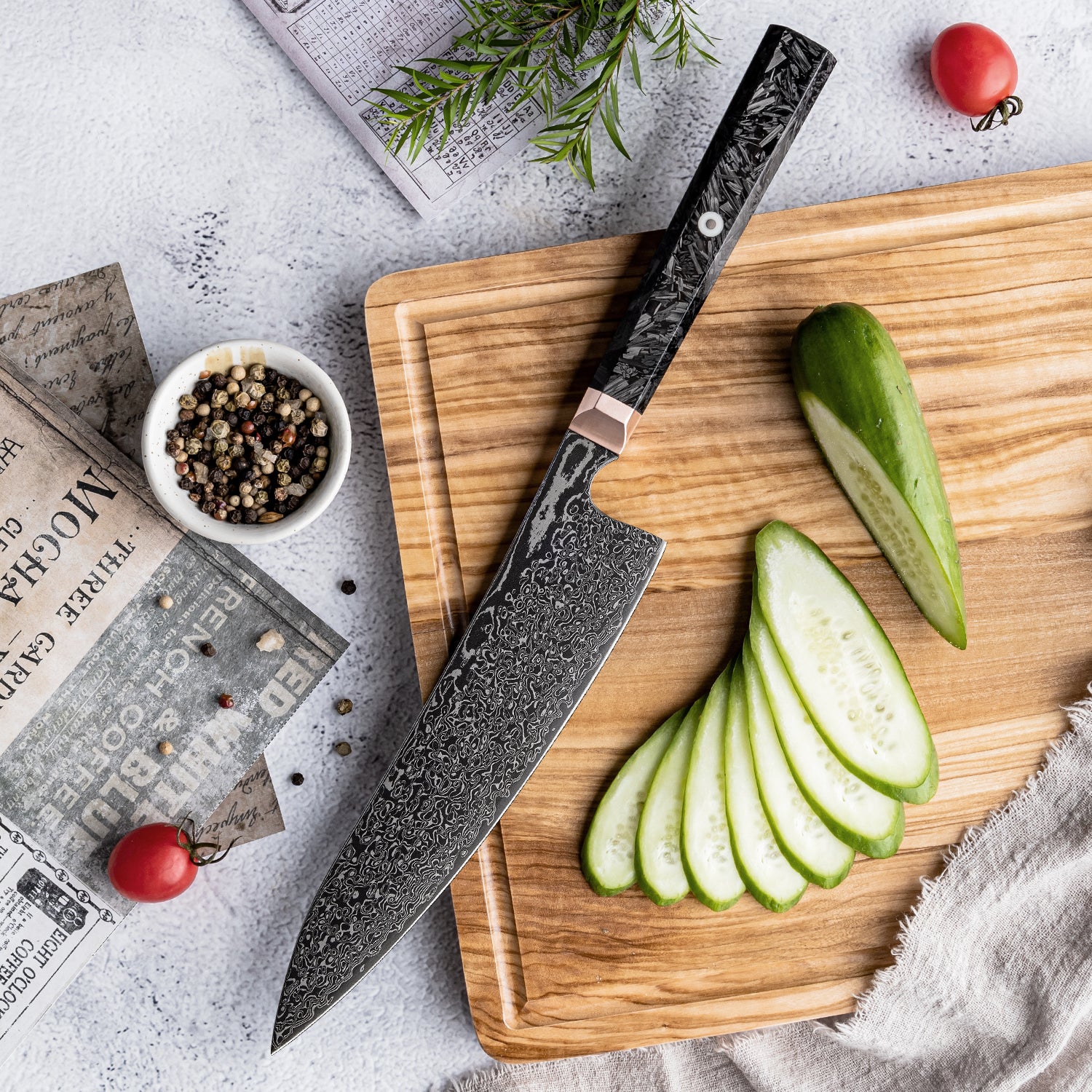 Chef's damascus knife on a wooden cutting board with sliced zucchini and red tomatoes.