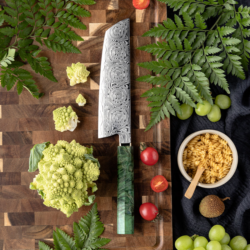 Decorative Rose Damascus Pattern nakiri knife on a wooden cutting board with vegetables and grains.