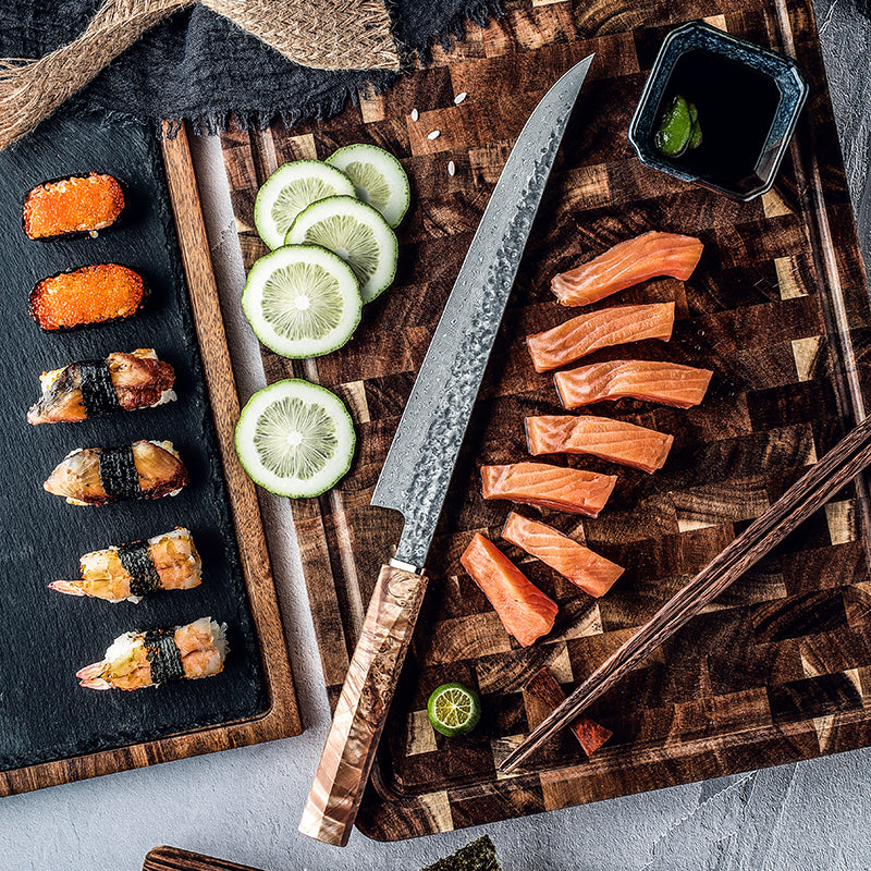 Sushi and sliced salmon on a wooden cutting board with a knife and lime slices.